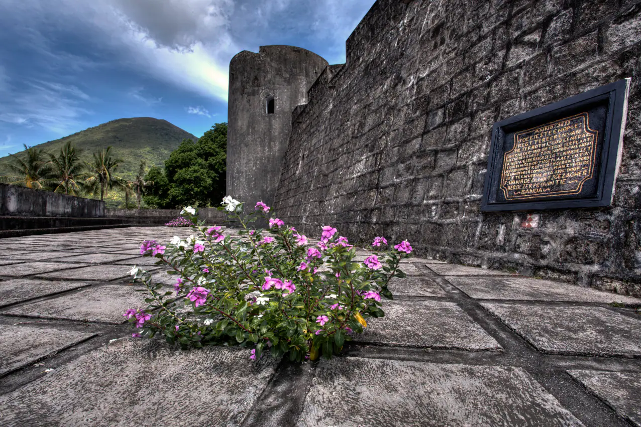 dutch-fort-on-banda-neira-in-the-banda-islands-with-the-volcano-in-the-background-with-coralia-liveaboard-in-indonesia